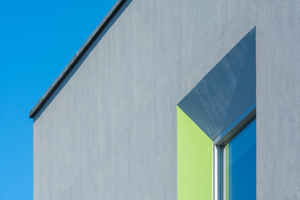 Strakke gevel met grijze siliconenpleister aan een moderne woning