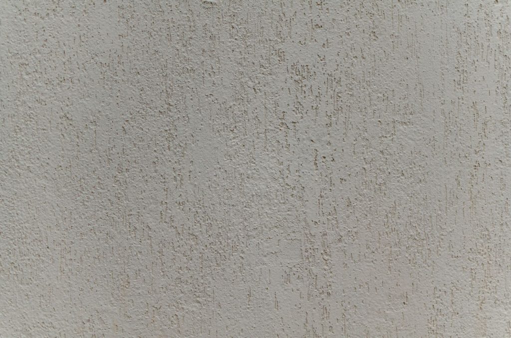 Close-up van de korrelstructuur van minerale crepi op een gevel